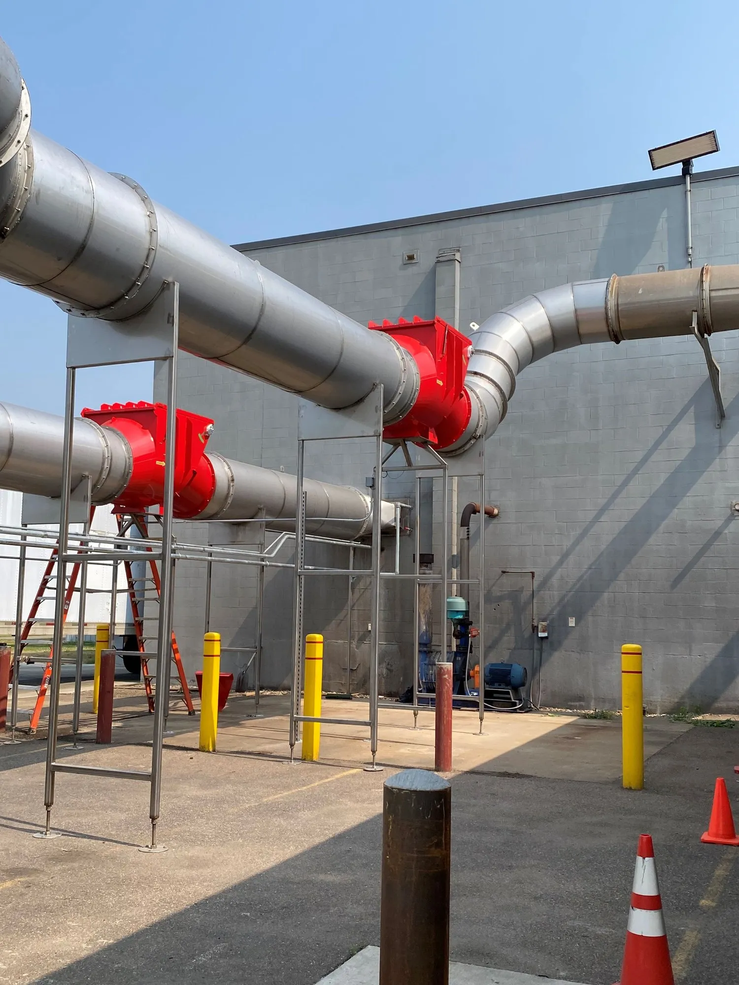 Two red high-speed abort gates mounted on large-diameter outdoor ducting carried on steel supports.